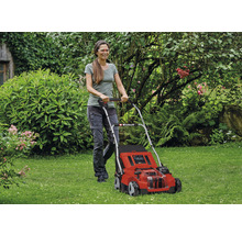 Frau bedient einen roten Einhell Rasenmäher im Garten.