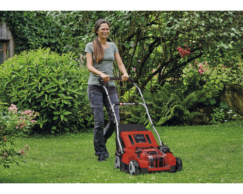 Frau bedient einen roten Einhell Rasenmäher im Garten.