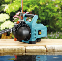 Gartenpumpe neben einem Teich auf einer Holzoberfläche