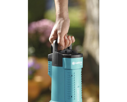 Eine Hand hält eine Gardena Gartenpumpe mit Tragegriff.