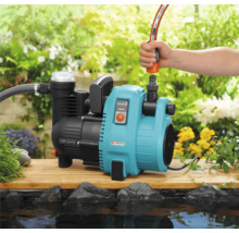 Gartenpumpe mit Schlauchanschluss neben einem Teich im Garten