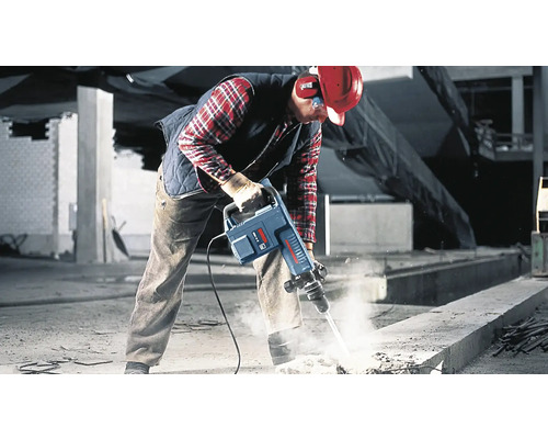 Ein Arbeiter verwendet einen Abbruchhammer auf einer Baustelle, um Beton aufzubrechen.