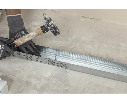 Handwerker befestigt Trockenbauprofil mit Hammer und Handschuhen.
