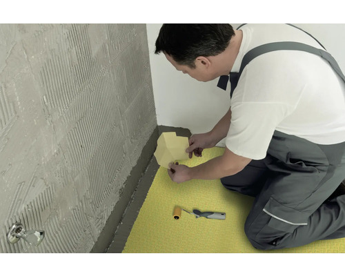 Handwerker bringt Dichtband in einem Badezimmer an