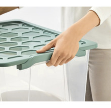 Person schließt einen transparenten Aufbewahrungsbehälter mit einem Deckel.