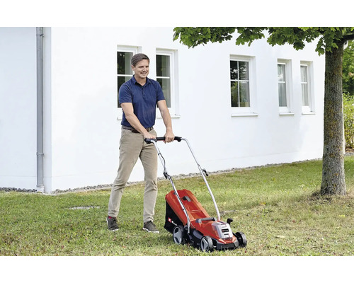 Mann mäht Rasen mit einem elektrischen Rasenmäher