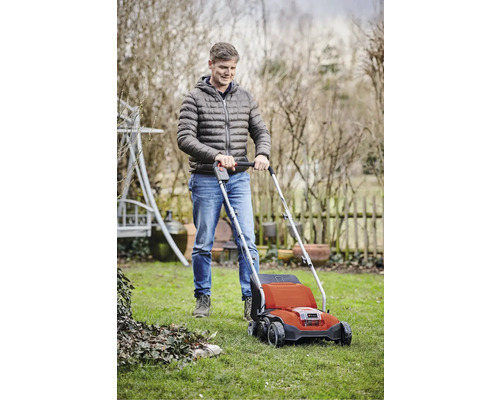 Ein Mann benutzt einen Rasenlüfter im Garten.