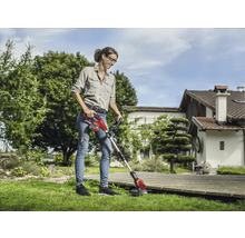 Frau mit Akku-Rasentrimmer bei der Gartenarbeit