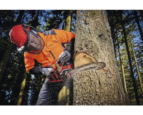 Mann mit Schutzkleidung fällt Baum mit einer Kettensäge