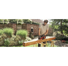 Mann hobelt Holzbalken im Garten mit einem Elektrohobel.