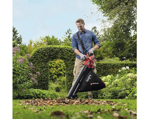 Ein Mann benutzt einen Laubsauger im Garten, um Laub zu entfernen.