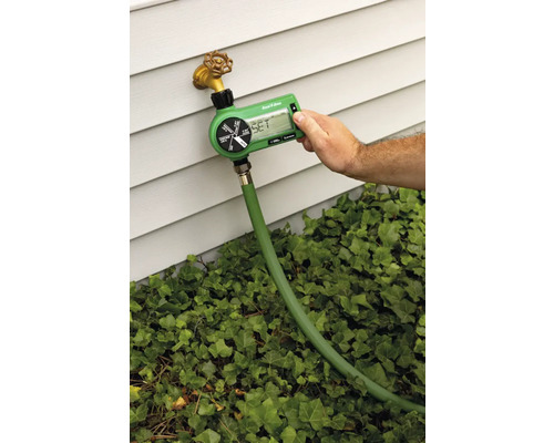 Gartenbewässerungscomputer an einem Wasserhahn mit Schlauch angeschlossen, die Bewässerung wird von einer Person eingestellt.