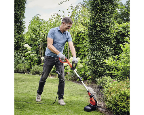 Mann verwendet Rasentrimmer in einem Garten.