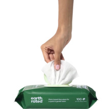 Eine Hand zieht ein Feuchttuch aus einer Packung Hundefeuchttücher.