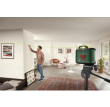 Raumszene mit einem Mann, der mit einem Laser-Nivelliergerät eine Linie an einer Wand markiert, Bosch Logo