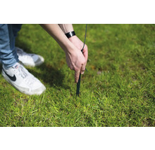 Person befestigt einen Hering im Gras