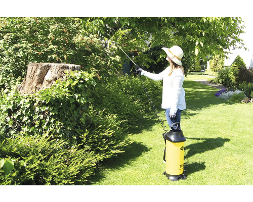 Gartenszene mit Frau, die Bäume mit einem Pflanzenschutzsprüher behandelt