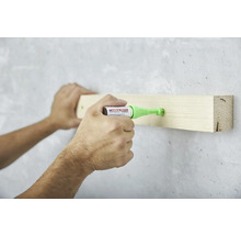 Anwendung des Edding 8870 Klebesiegelstiftes zum Befestigen eines Holzstücks an einer Wand.