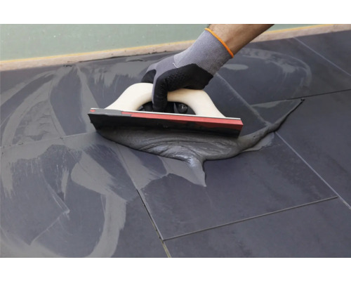 Fliesenleger mit Fugengummi beim Verfugen von Fliesen