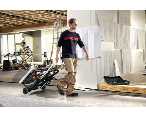 Mann transportiert eine Metabo Tischkreissäge im Innenraum.
