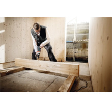 Ein Mann bohrt mit einer Bohrmaschine in einem mit Holz verkleideten Raum.