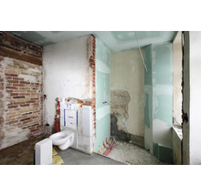 Badezimmerbaustelle mit Ziegelwand, Toilette und Trockenbau