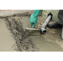 Handwerker mit Bürste beim Verfugen eines Bodens mit Fugenmasse.