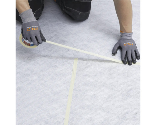 Handwerker verklebt Abdeckvlies mit Klebeband auf dem Boden