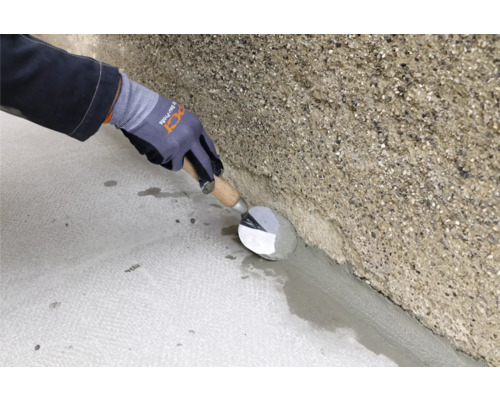 Handwerker glättet mit einer Mauerkelle Zement an einer Wand.