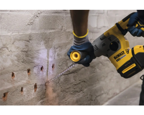 Eine Person bohrt mit einem Bohrhammer Löcher in eine Wand.