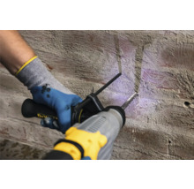 Eine Person bohrt mit einem Bohrhammer in eine Ziegelwand