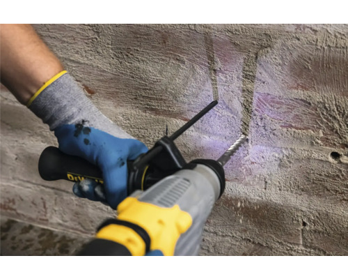 Eine Person bohrt mit einem Bohrhammer in eine Ziegelwand