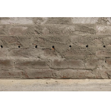Eine Ziegelwand mit Bohrlöchern.