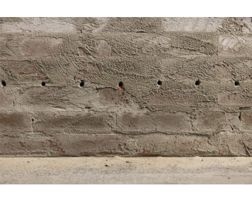 Eine Ziegelwand mit Bohrlöchern.