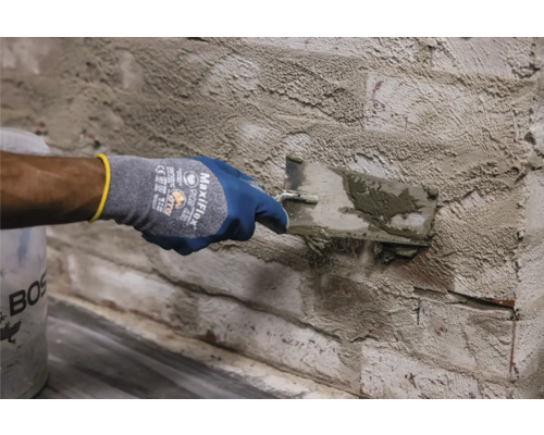 Eine Person trägt Putz auf eine Ziegelwand mit einer Kelle auf