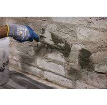 Handwerker verfugt eine Backsteinwand mit einer Spachtel und Fugenmörtel