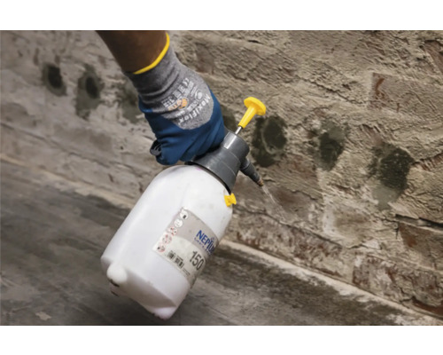 Anwendung einer Sprühflasche auf einer Ziegelwand.