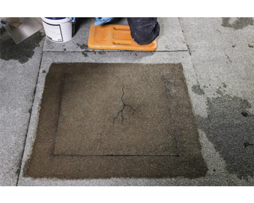 Dachreparatur mit Reparaturmasse auf einem Flachdach.