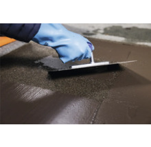 Handwerker glättet Nivelliermasse mit einer Glättkelle.