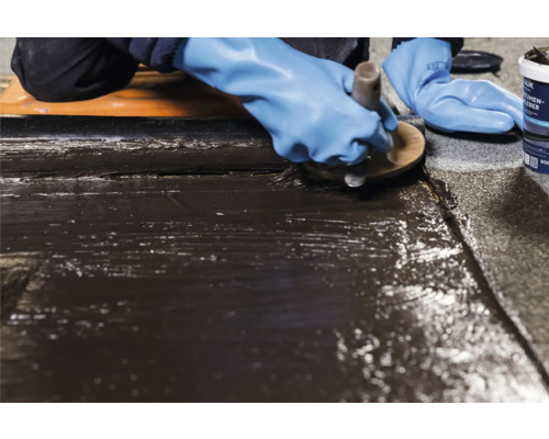 Verarbeiter trägt Bitumenkleber auf