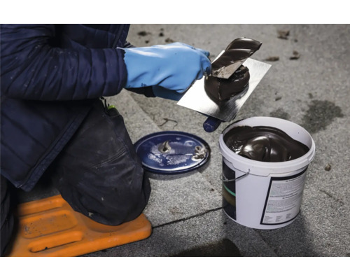 Handwerker mit Spachtel und Eimer Dachabdichtungsmasse