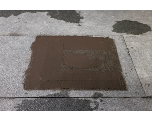 Dachreparatur mit Bitumenanstrich auf einer Dachfläche.