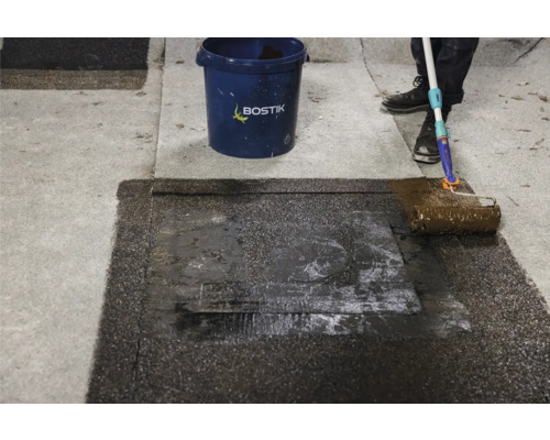 Anwendung von Dachbeschichtung mit Farbroller auf einer Dachfläche. Bostik Logo ist sichtbar.