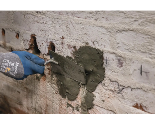 Mauersanierung mit einer Maurerkelle und Fugenmörtel