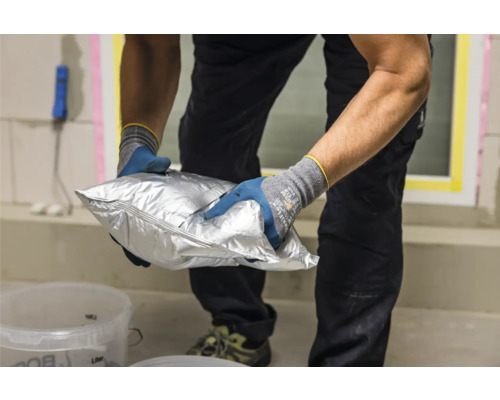 Eine Person hält eine versiegelte Verpackung mit Baumaterial.