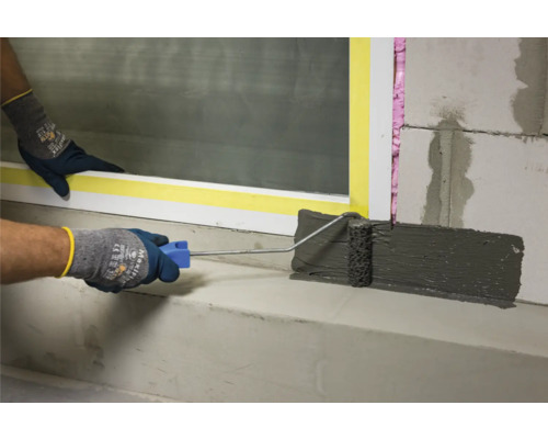 Auftragen einer Dichtungsschlämme mit einer Rolle auf eine Fensterbank.