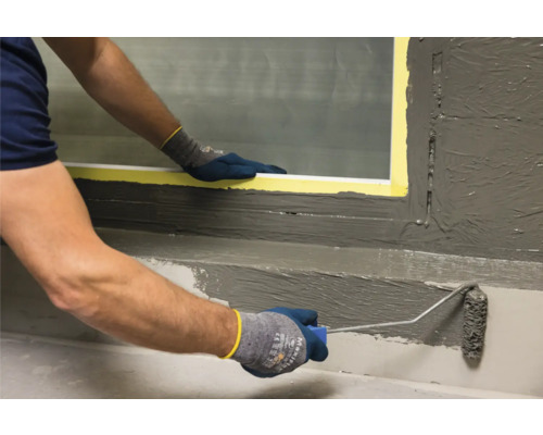 Person trägt Abdichtung mit einer Farbwalze auf