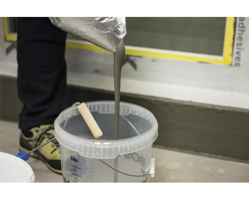 Fließspachtel wird in einen Eimer gegossen.