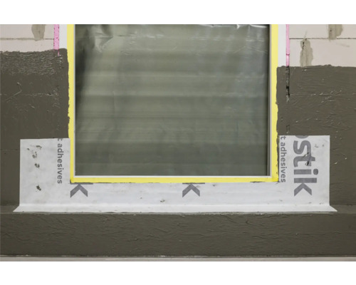 Detailansicht eines Fensters mit Dichtband und Abdichtung an einer Wand.