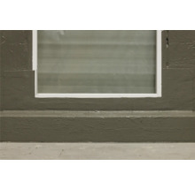Nahaufnahme eines Kellerfensters mit gestrichenem Rahmen und Wand